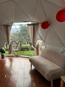 a room with a couch in a tent with a large window at DOMO Roca Glamping Suesca in Suesca
