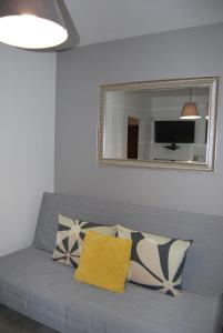 a gray couch with pillows on it with a mirror at Magnolia Centrum Studio in Wrocław