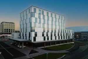 a tall glass building with a bus stop in front of it at Distinction Invercargill Hotel in Invercargill