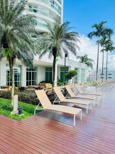 a row of lounge chairs on a boardwalk with palm trees at Studio Mandarin + spectacular view + Umarizal in Belém