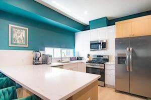 a kitchen with white cabinets and blue walls at Jardin Noir at Case Collective in North Hollywood