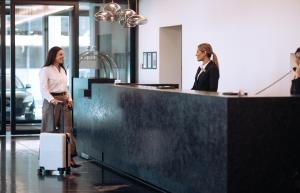 two women standing in an office with their luggage at Distinction Invercargill Hotel in Invercargill