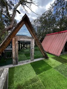 a frame house with a red roof on the grass at Mini Cabaña Roca Glamping in Suesca