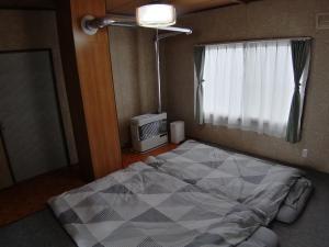 ein Schlafzimmer mit einem großen Bett und einem Fenster in der Unterkunft あらさんち in Asahikawa