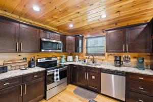 a kitchen with wooden cabinets and stainless steel appliances at Grizzly Glam in Gatlinburg