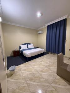 a bedroom with a bed and a blue curtain at شركه أركان الذهبيه الحديثه للشقق المخدومه in Abha
