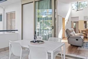 a white dining room with a white table and chairs at Immaculate Riverside Apartment With Heated Pool in Noosaville