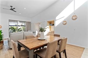 a dining room with a wooden table and chairs at Immaculate Riverside Apartment With Heated Pool in Noosaville