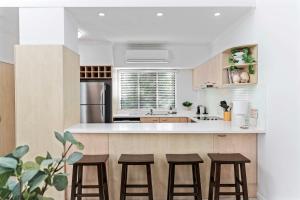 a kitchen with a counter with stools in it at Immaculate Riverside Apartment With Heated Pool in Noosaville +13 photos