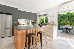 a kitchen with a counter and two stools at Whispering Waves Pet Friendly Steps to Beach in Peregian Beach