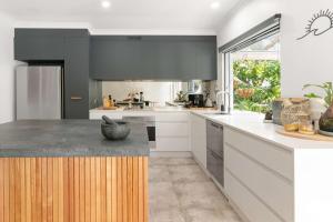 a kitchen with white cabinets and a large window at Whispering Waves Pet Friendly Steps to Beach in Peregian Beach