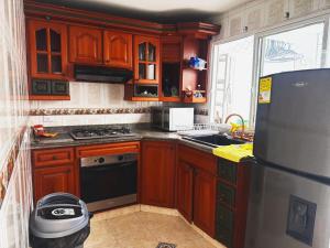 a kitchen with wooden cabinets and a black refrigerator at Casa Aire y Luz in Pereira
