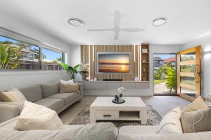 a living room with a couch and a tv at Spacious 4-Bed Coastal Home with Pool in Mooloolaba