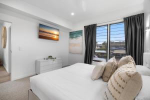 a white bedroom with a bed and a large window at Spacious 4-Bed Coastal Home with Pool in Mooloolaba +16 photos