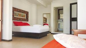 a bedroom with a bed with red pillows and a mirror at El Fuerte Beach Apartments in Mahahual