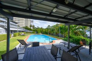 a patio with a table and chairs and a swimming pool at Beach Lodges in Hamilton Island