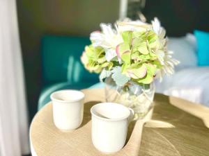 a vase with flowers and two cups on a table at Ocean View Suite 2 Beds Wi-Fi Netflix in Gold Coast