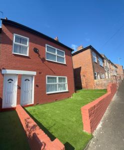 a brick house with a lawn in front of it at Bright Housing in Newcastle upon Tyne
