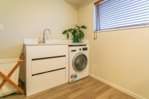 a laundry room with a washing machine and a sink at The Bach in Coromandel Town