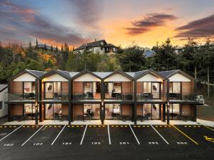 a building in a parking lot with a sunset in the background at Archway Motels & Chalets in Wanaka