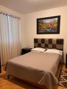 ein Schlafzimmer mit einem Bett und einem Gemälde an der Wand in der Unterkunft Hotel Conquistador in Andahuaylas