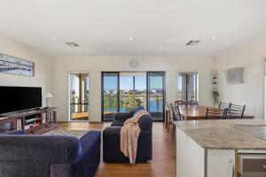 a living room with two blue couches and a kitchen at 41 Blanche Pde, Hindmarsh Island in Hindmarsh Island
