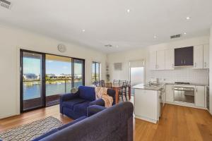 a living room with a blue couch and a kitchen at 41 Blanche Pde, Hindmarsh Island in Hindmarsh Island