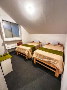 two beds in a small room with a window at Eco Bunnu Inn Santa Ana in Cusco