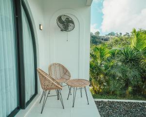 two chairs and a table on a porch with a clock at Hideout Kintamani and Hot Spring in Kintamani