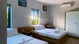 a room with two beds and two windows at Hưng Phát Hotel Nghệ An in Vinh