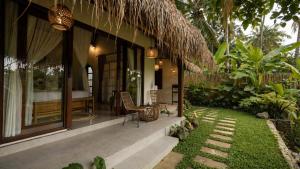 a resort with a bed and a patio with a garden at D'Penglipuran Jungle House in Susut
