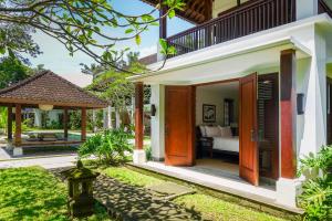 a villa with a bedroom and a garden at Bumi Kinar Heritage in Ubud