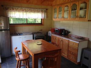 a kitchen with a wooden table and a small table with chairs at Bungalow Playa Linda I in Pucón