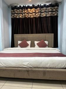 a bed with red pillows in front of a window at The Human Stay in Indore