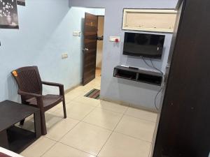 a small living room with a television and a chair at The Human Stay in Indore
