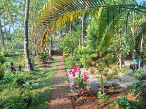 a garden with pink flowers and palm trees at Kkheritage Homestay in Thottada