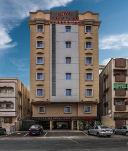 a tall building with cars parked in a parking lot at Al Itqan Apart-hotel in Jeddah