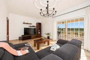 a living room with a couch and a tv at Villa Entrecolinas in São Bartolomeu de Messines