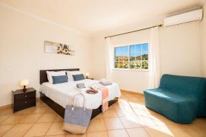 a bedroom with a bed and a blue chair at Villa Entrecolinas in São Bartolomeu de Messines +25 photos