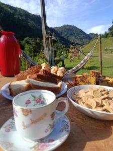 un tavolo con piatti di pane e una tazza di caffè di Sítio Do Manacá a Domingos Martins Altre 41 foto