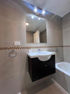 a bathroom with a sink and a mirror and a tub at Punta Flecha in Puerto Madryn