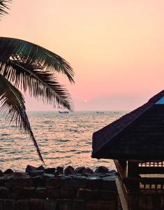 a palm tree and the ocean at sunset at Sea View Balcony room - Tide End Beach Villa in Pallipuram +5 photos