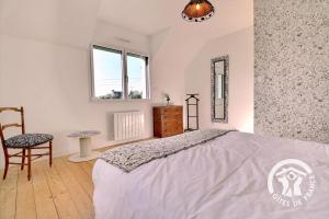 a bedroom with a bed and a chair and a window at Le cerisier in Cancale