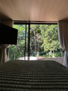 a bedroom with a bed with a large window at Chalé Moov in Guarapari