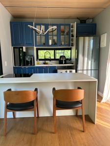 a kitchen with blue cabinets and two chairs at Chalé Moov in Guarapari
