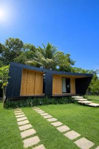 a house with a black roof and a grass yard at Chalé Moov in Guarapari