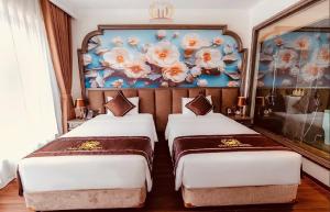 two beds in a room with a painting on the wall at Bảo Long Lào Cai Hotel in Lao Cai +148 photos