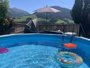 a swimming pool with a raft and an umbrella at TraumLodge in Kleinsonnberg