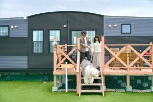a couple standing next to a dog on a house at Solana 鴨川 in Kamogawa