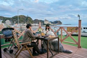 a man and a woman sitting at a table with a dog at Solana 鴨川 in Kamogawa